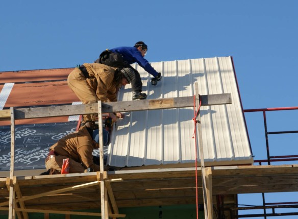 Guy, Devin, and Spartan installing the metal panel
