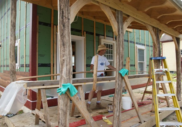 Andy dipping siding board in trough of stain